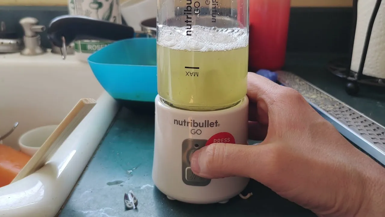 Blender cup soaking in soapy water with brush and oats nearby