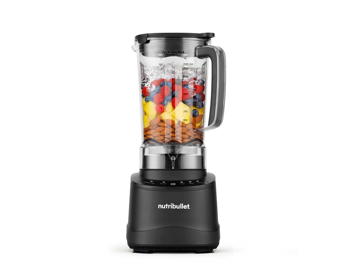 Blender pitcher being filled with spinach and banana before blending