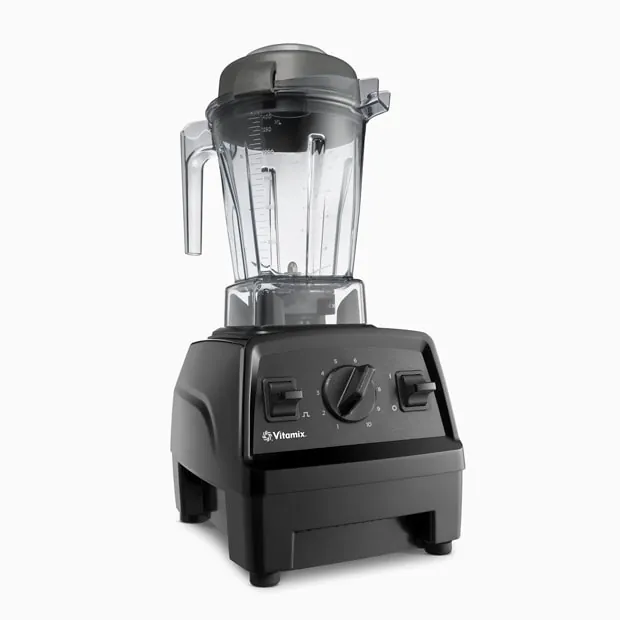 A Breville and Ninja blender with protein shakes on a white tile counter, Vitamix blurred in background.