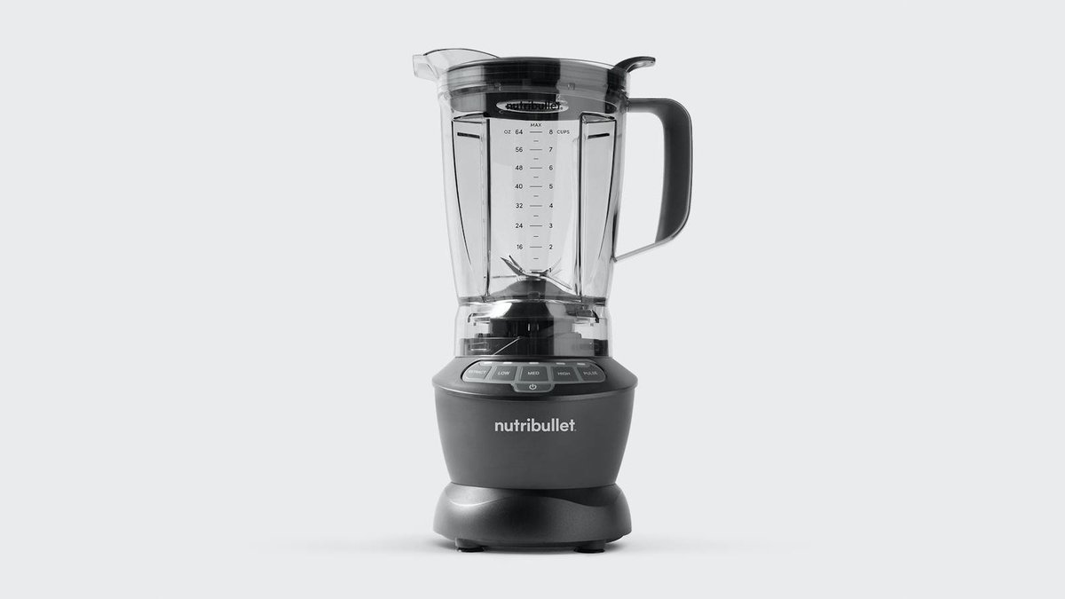 Bullet blender cup of soup on a kitchen counter beside a saucepan