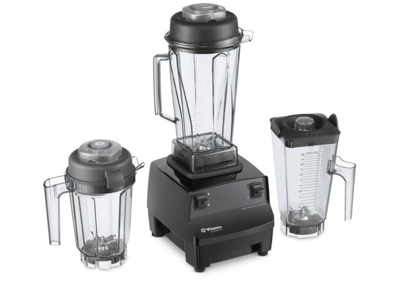 A clear Vitamix 40 ounce blender container sits on a bright marble kitchen counter.
