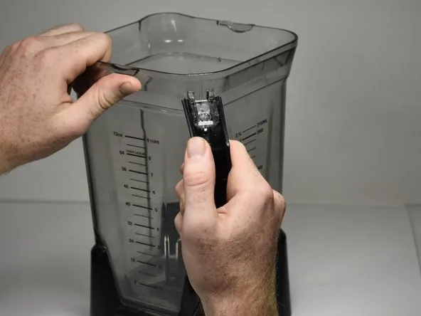 Close up hands inspecting the handle connection on a Ninja blender pitcher.