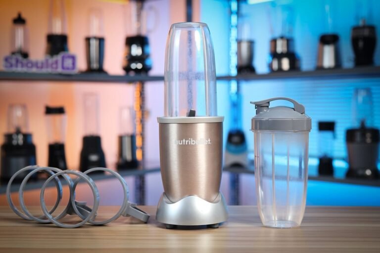 Compact personal blender on a kitchen counter beside a green smoothie