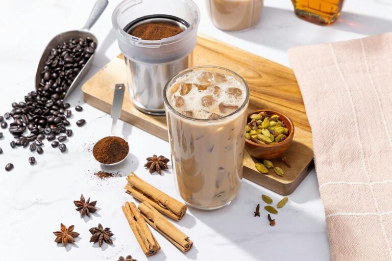 Empty personal blender beside a steaming mug of hot coffee on a kitchen counter