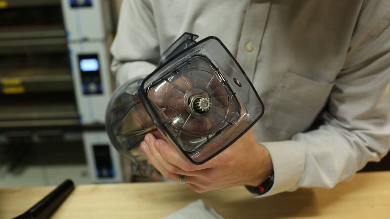 Fully assembled Vitamix blender with clear container locked onto metal base on a light marble countertop.