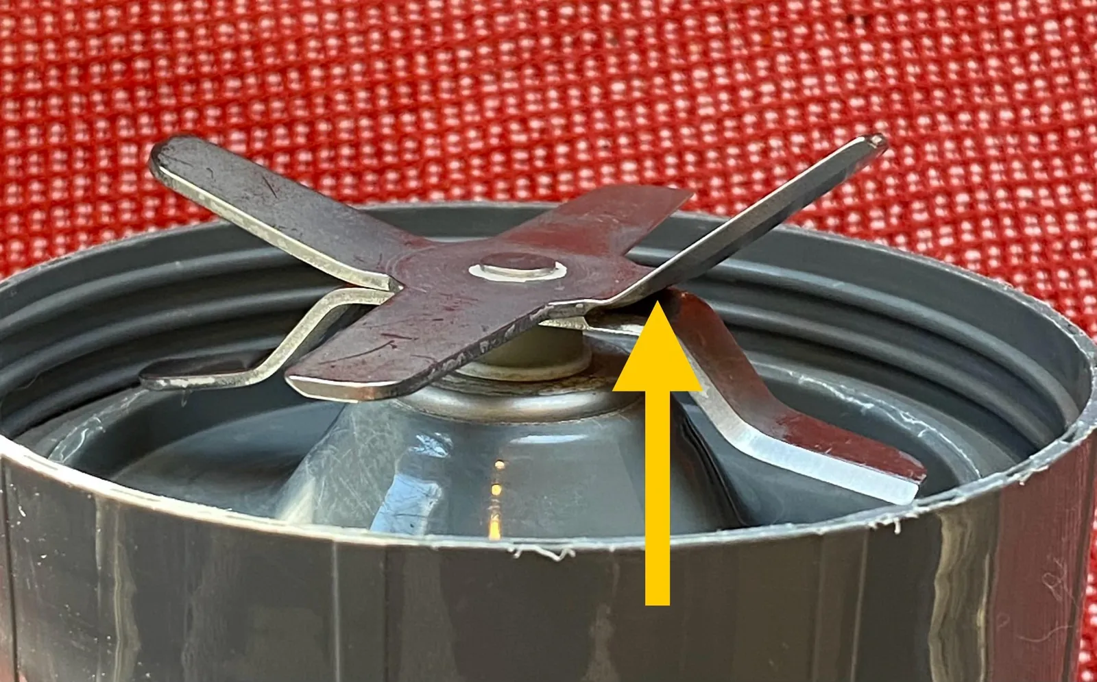 Hand wiping a blender base with a damp cloth on a kitchen counter
