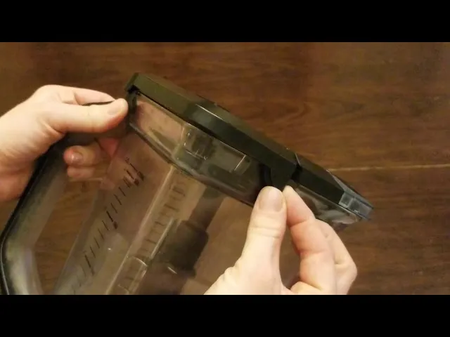 Hands carefully attempting to release a stuck lid from a Ninja blender.