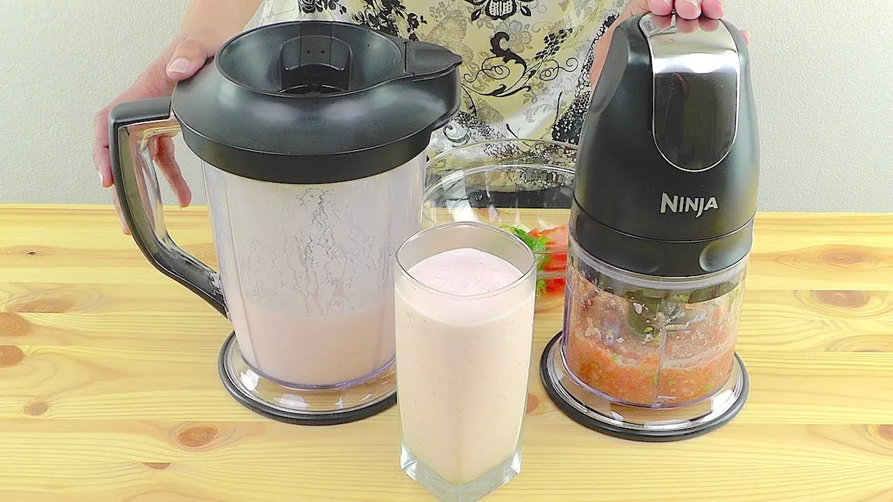 Hands carefully placing the blade assembly into a Ninja blender pitcher for assembly.