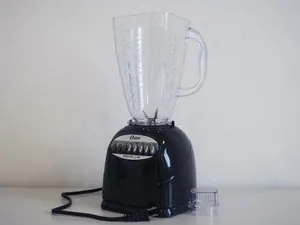 Hands locking a glass jar onto an Oster blender base