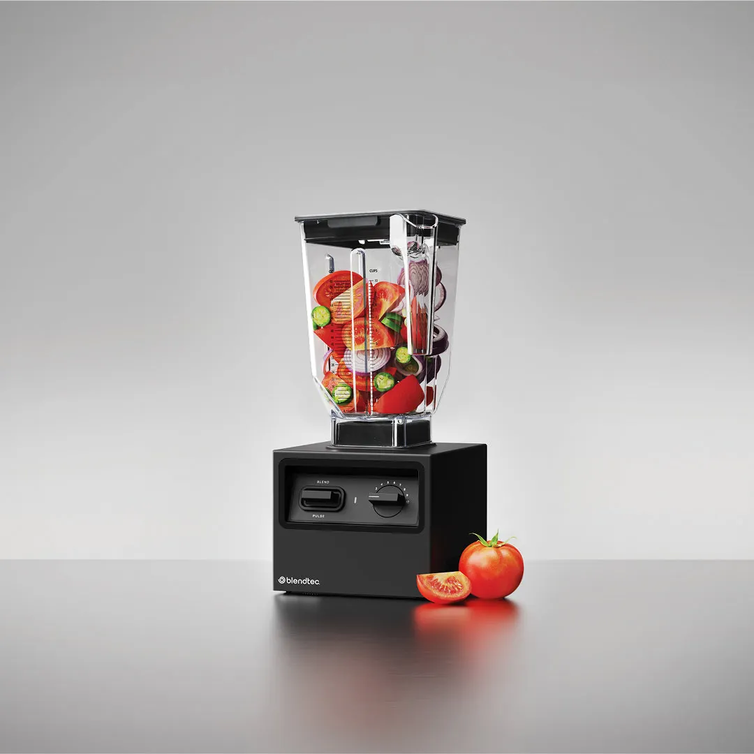 Hands securing the lid on a running Vitamix blender for safe operation