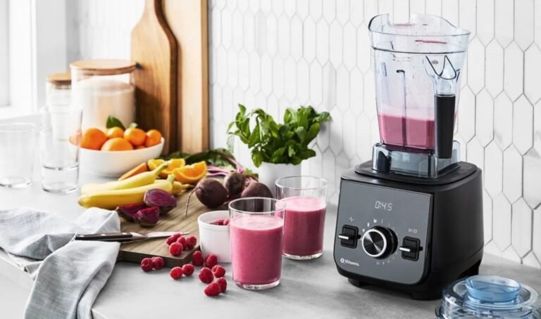 A high-performance blender surrounded by fresh ingredients on a modern kitchen countertop.