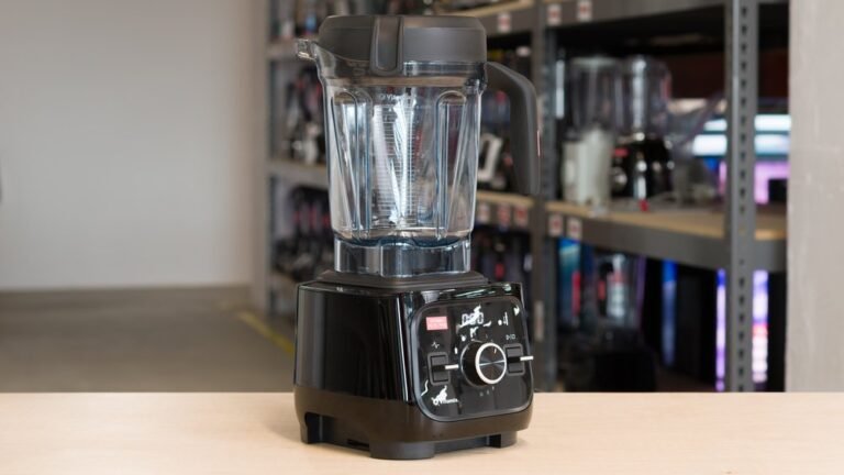 A high-performance Vitamix Alta Pro blender filled with fresh greens on a marble countertop.