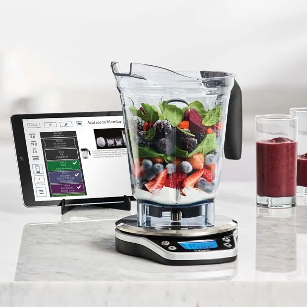 A home cook using a smartphone app while preparing food with a smart scale.