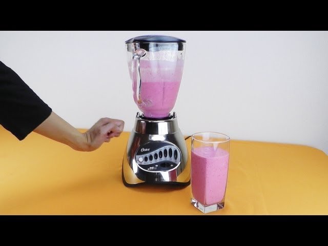 Layered smoothie ingredients in a glass blender jar on a kitchen counter