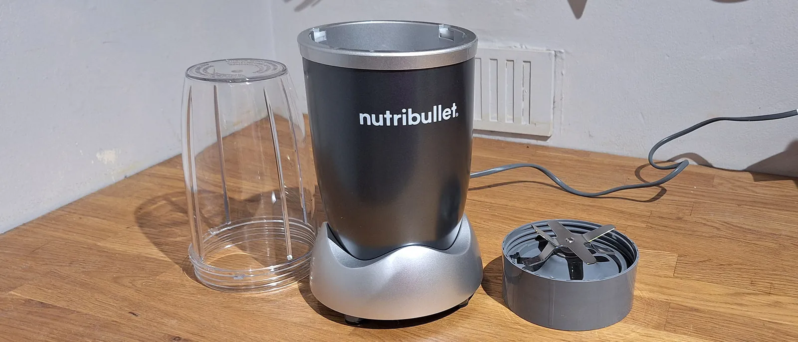 Nutribullet 600 blending small frozen fruit pieces beside a cup of large chunks