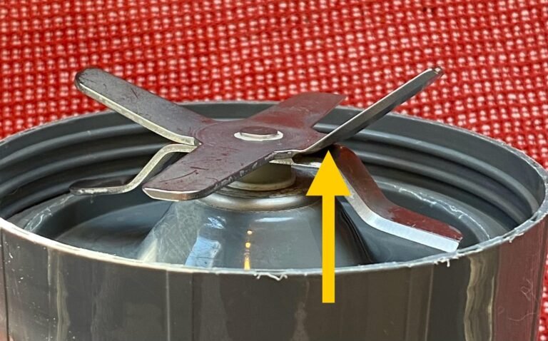 Nutribullet blender blade base unscrewed next to cleaning supplies on a kitchen counter