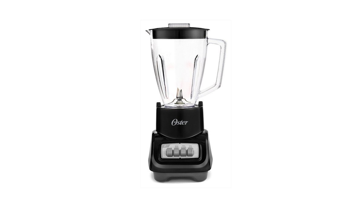 Oster blender with glass jar on a kitchen counter beside frozen fruit