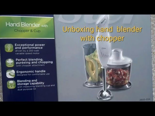 Oster hand blender standing on a kitchen counter beside a pot of soup