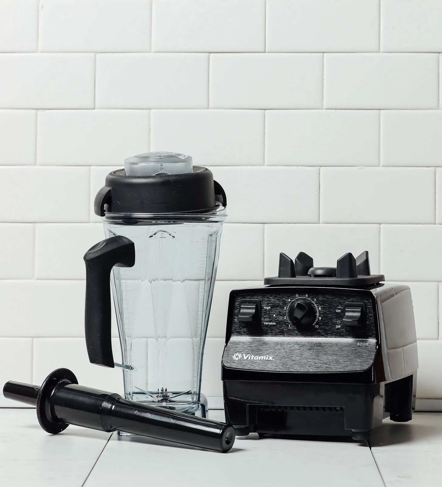 A perfectly smooth green smoothie pours from a high-performance blender into a glass.