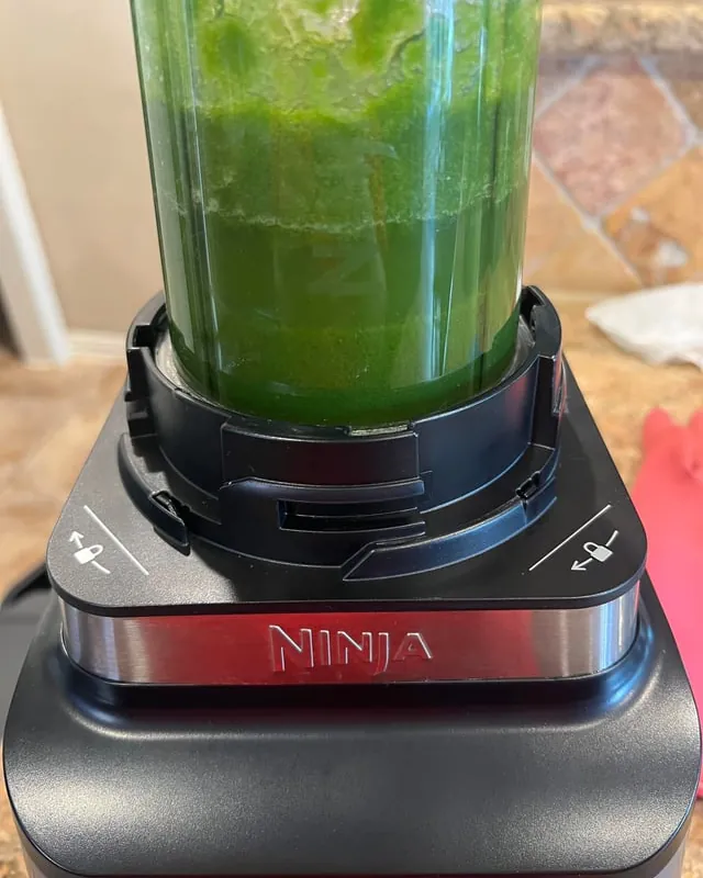 A person prepares to remove a stuck Ninja blender cup from the base.