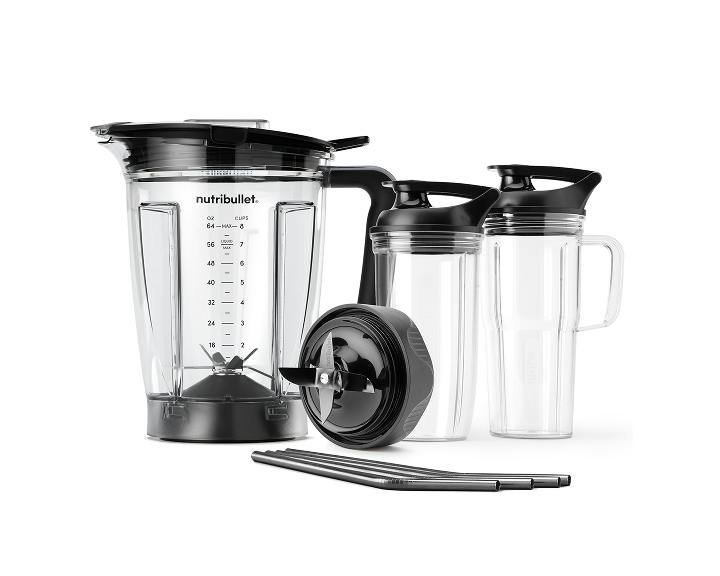 Personal blender on a kitchen counter beside fresh fruit and greens
