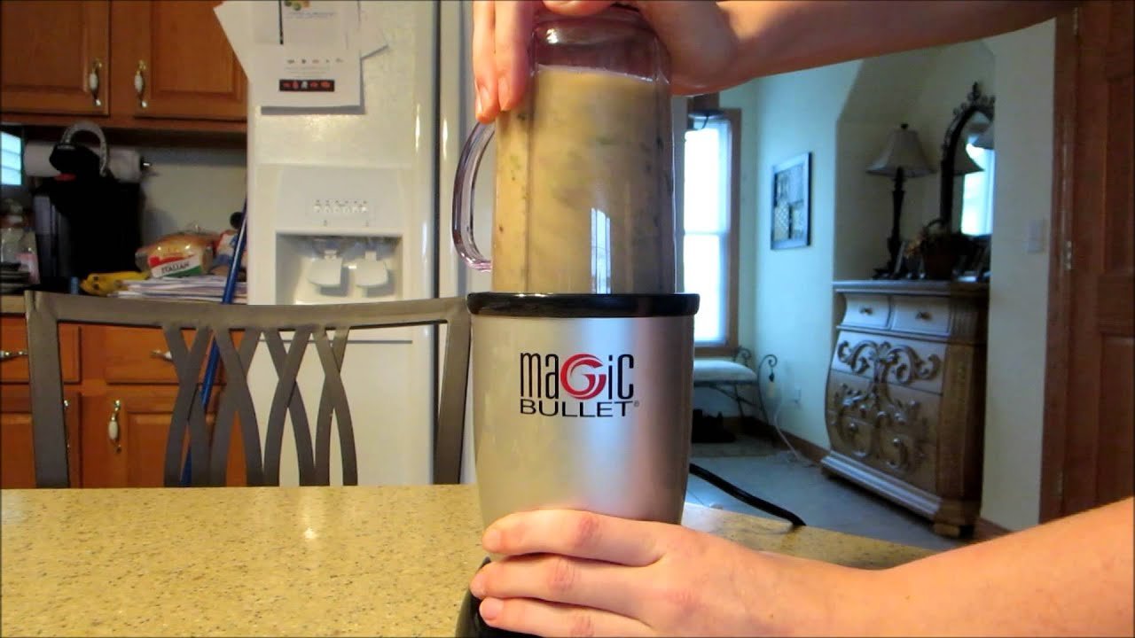 A personal blender on a kitchen counter surrounded by fresh smoothie ingredients