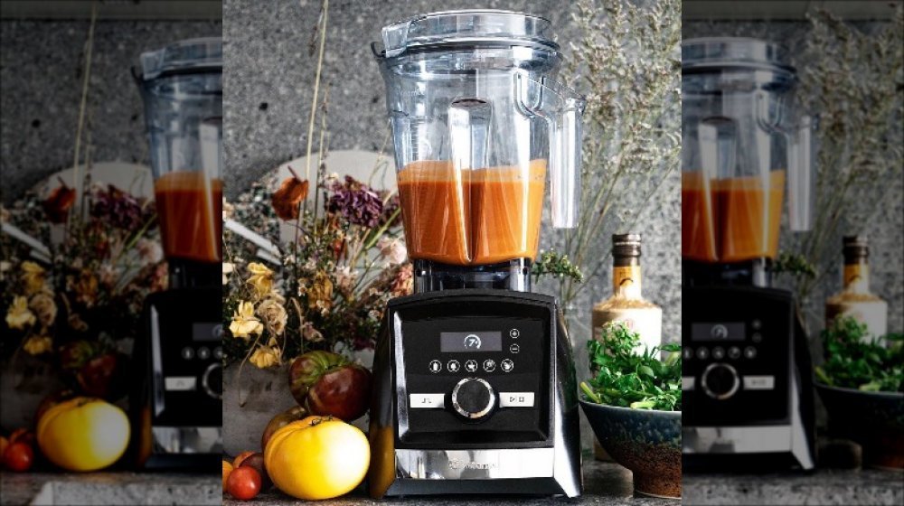 A professional high-performance blender sits on a modern kitchen counter during the day.