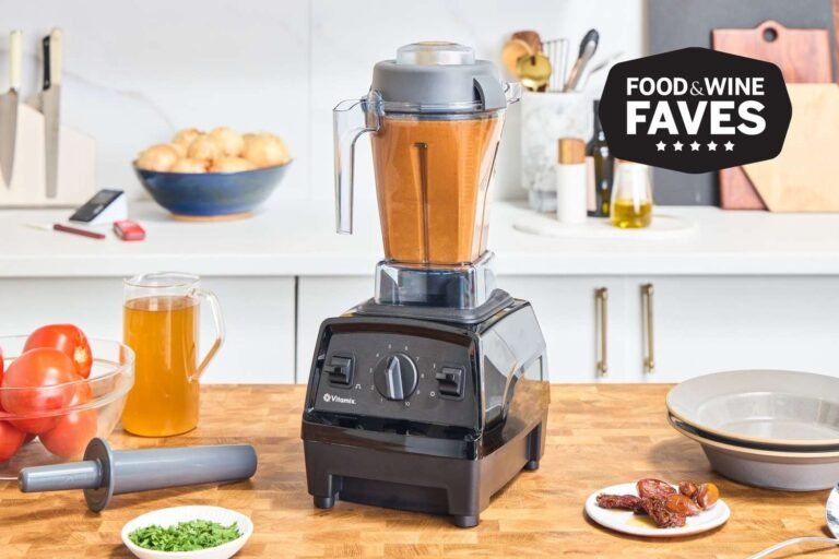 A professional kitchen counter displaying a powerful Vitamix blender alongside a food processor.
