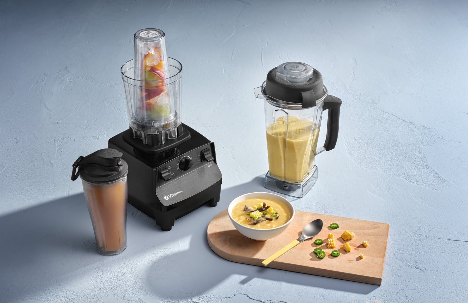 A professional Vitamix blender sits on a marble counter alongside fresh whole produce.