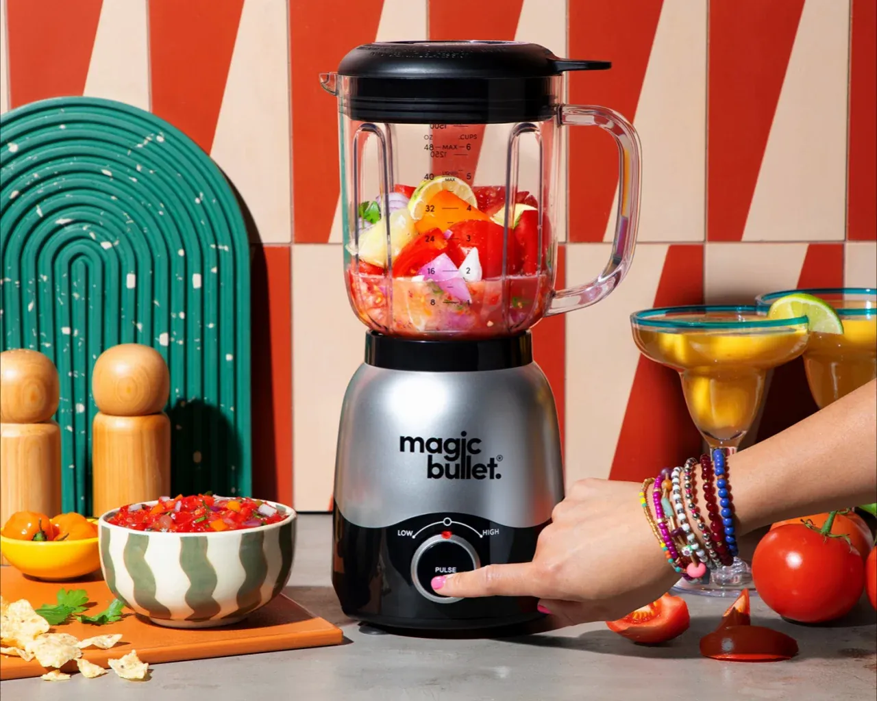 A small blender cup next to a large countertop blender and soup