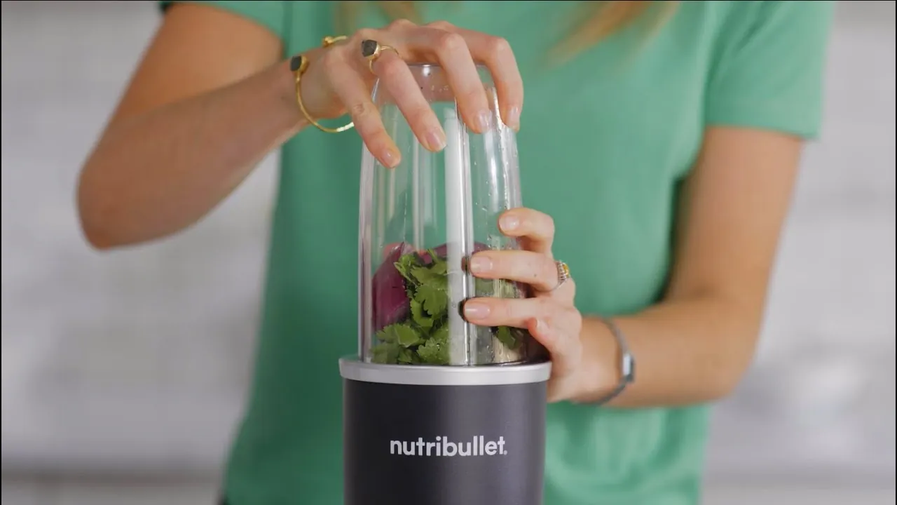 Small personal blender blending soft fruit on a kitchen counter