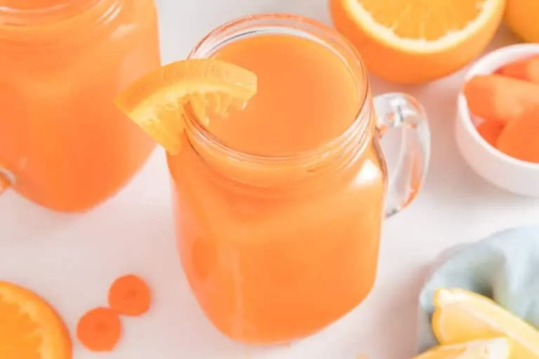 Straining carrot pulp through a mesh sieve into a glass bowl