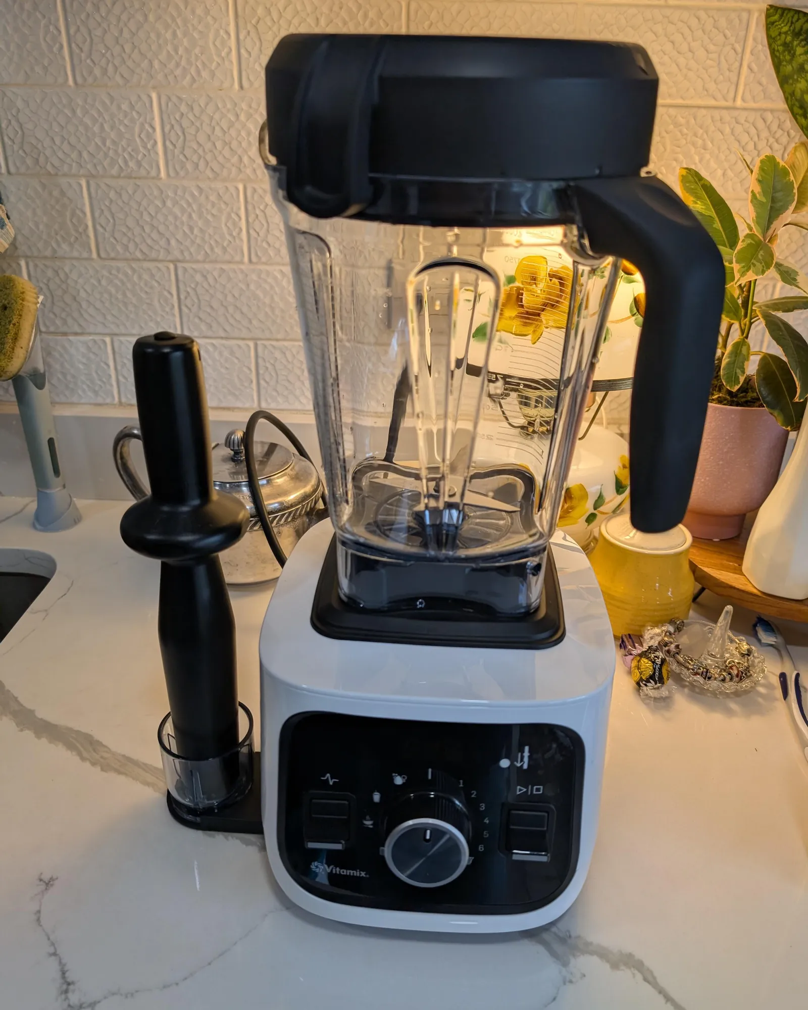 A tall high-performance blender placed on a counter with very little overhead cabinet space.