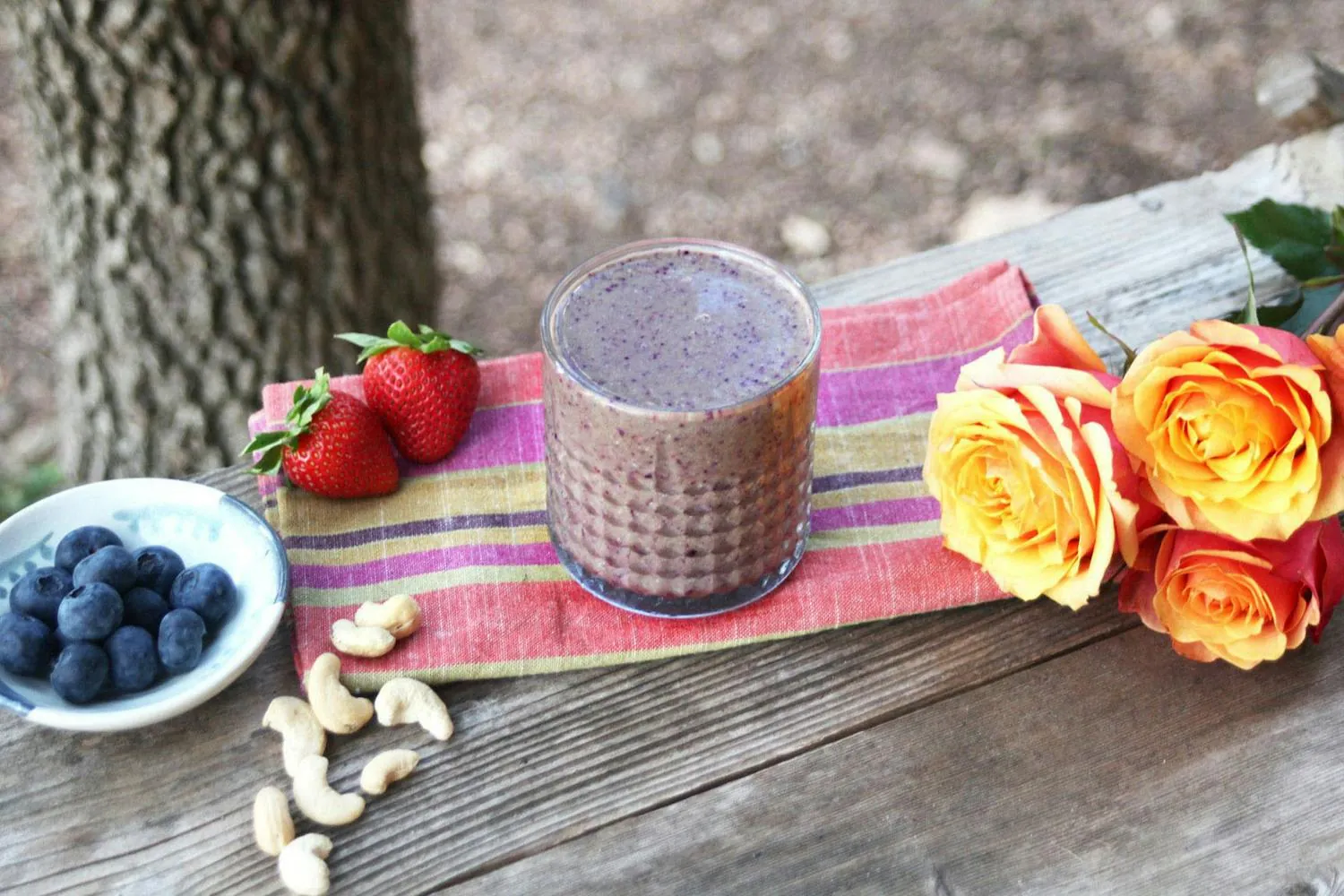 Thick cashew paste stuck inside a personal blender cup beside a food processor