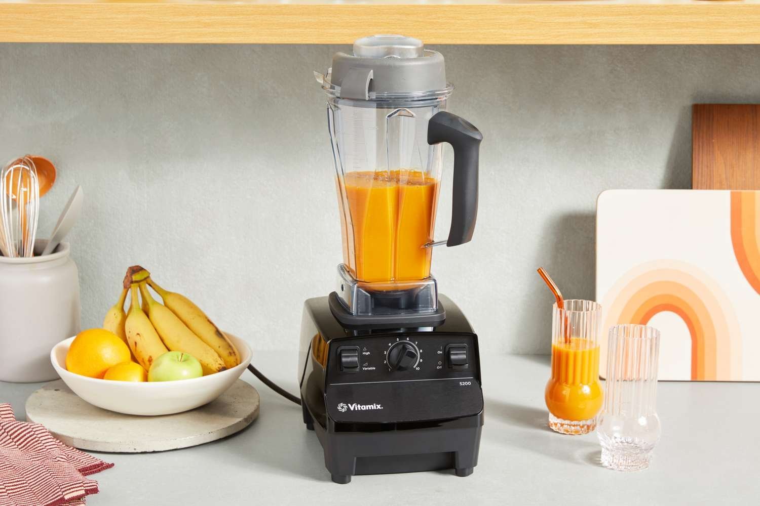 Vitamix blender blending a vibrant green smoothie on a marble countertop in natural light