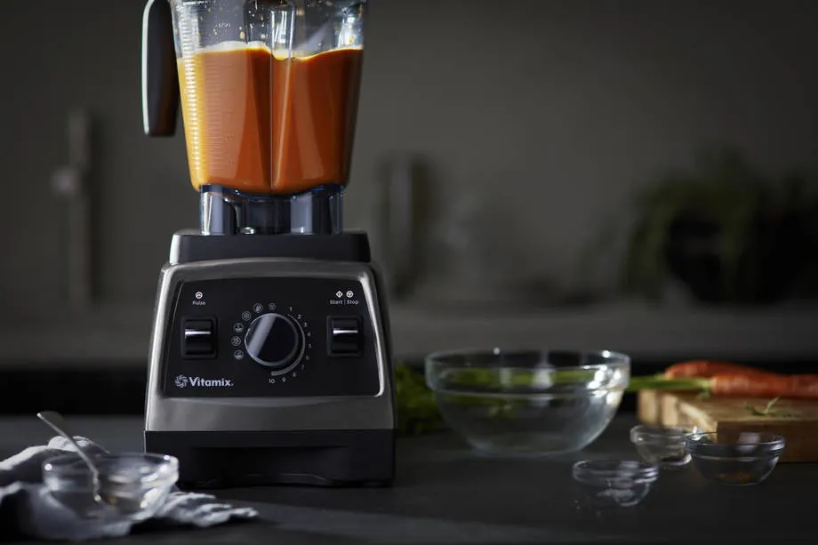 Vitamix container filled with raw unpeeled apples celery stalks and kale stems showing fibrous texture