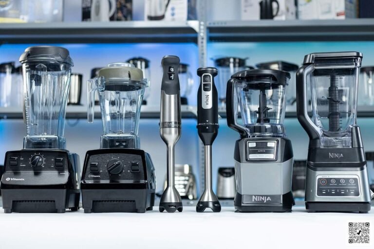 A Vitamix and a Ninja blender stand together on a clean kitchen counter.