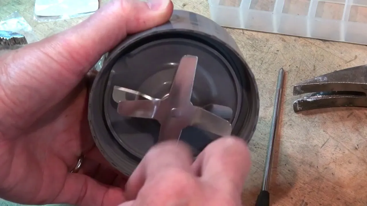 Woman at kitchen sink inspecting blender cup and blade assembly before washing